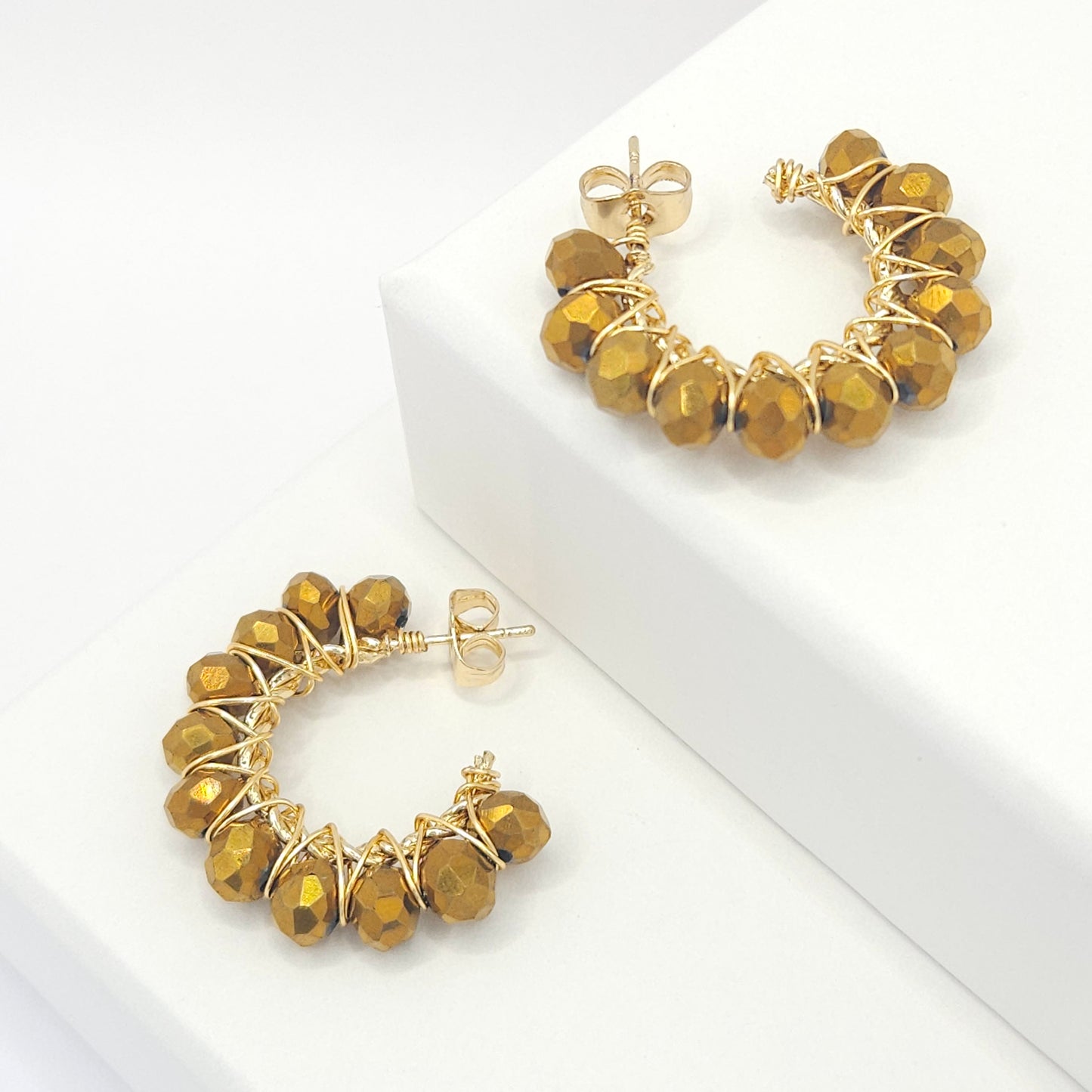Golden hoops with delicate chocolate faceted rondelle glass beads, both lying on white bases