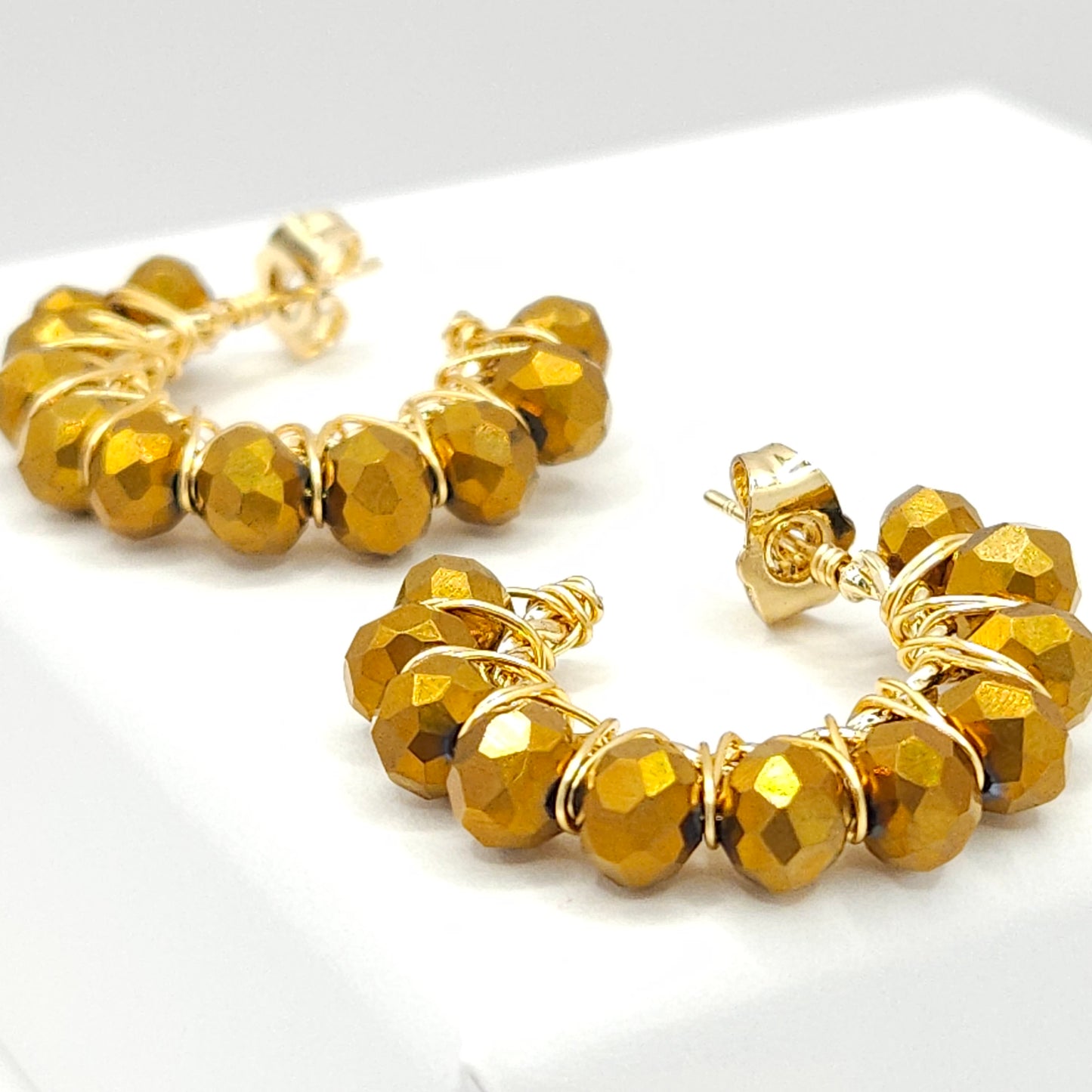 Close-up of golden hoops with chocolate faceted rondelle beads, focused on lower right details, blurring toward upper left corner