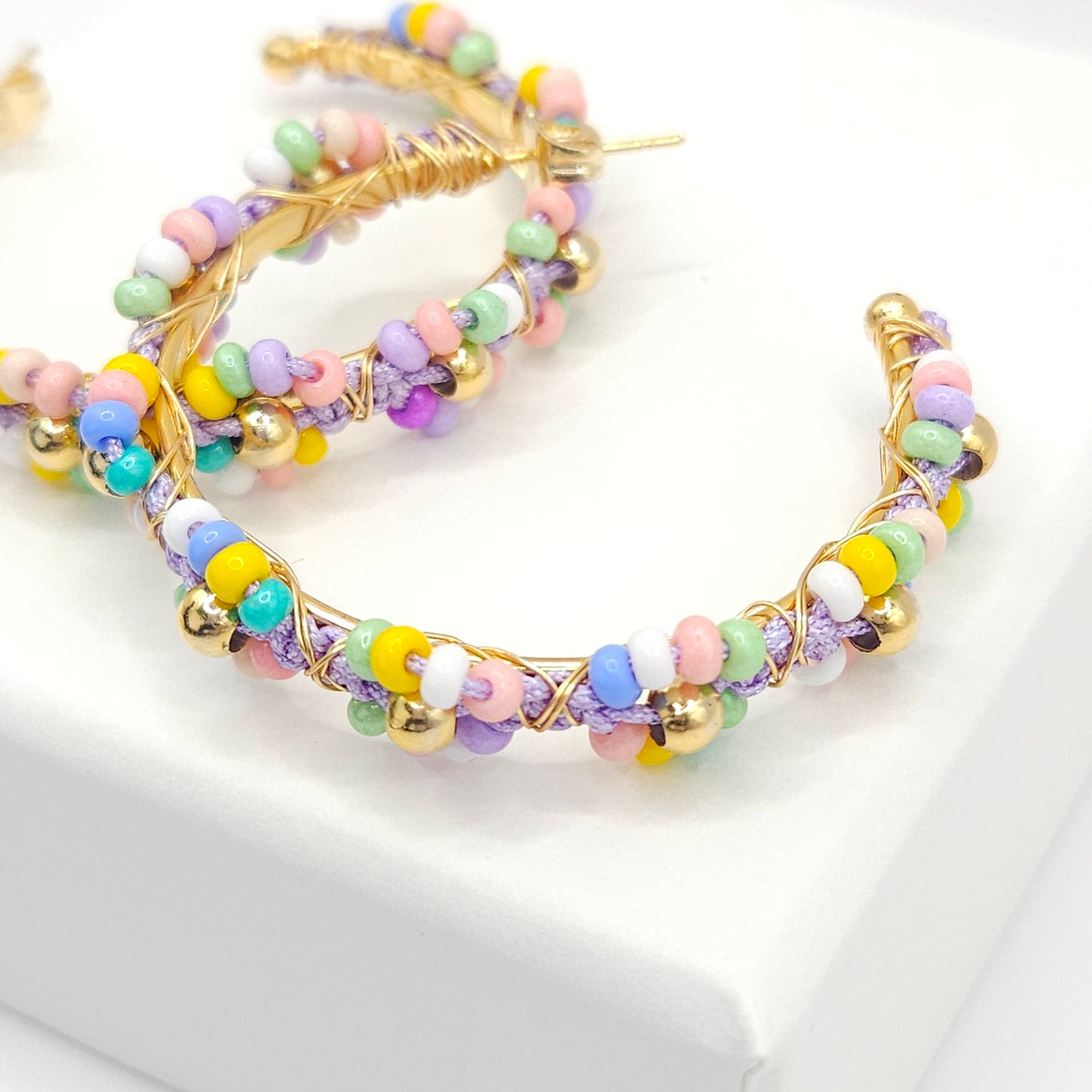 Close-up of golden hoop soft pastel Czech beads, focused on lower right detail, blurring toward the upper left corner