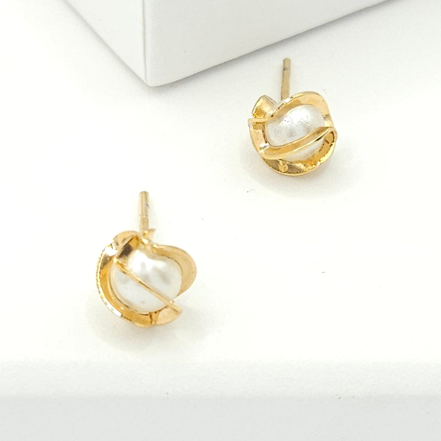 Floral-inspired stud earrings, with a pearl delicately cradled within intricate, goldtone lines