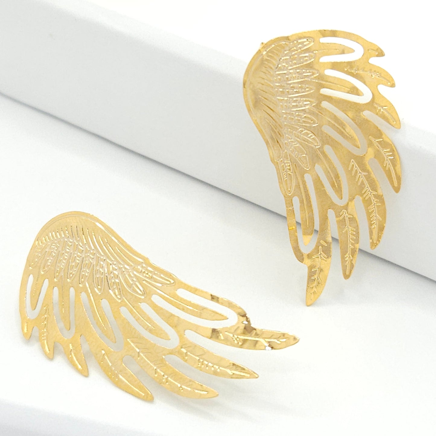 Large stud earrings, resembling the feathered wings of an angel. Each earring boasts feathered wings meticulously crafted from 18k gold-plated bronze