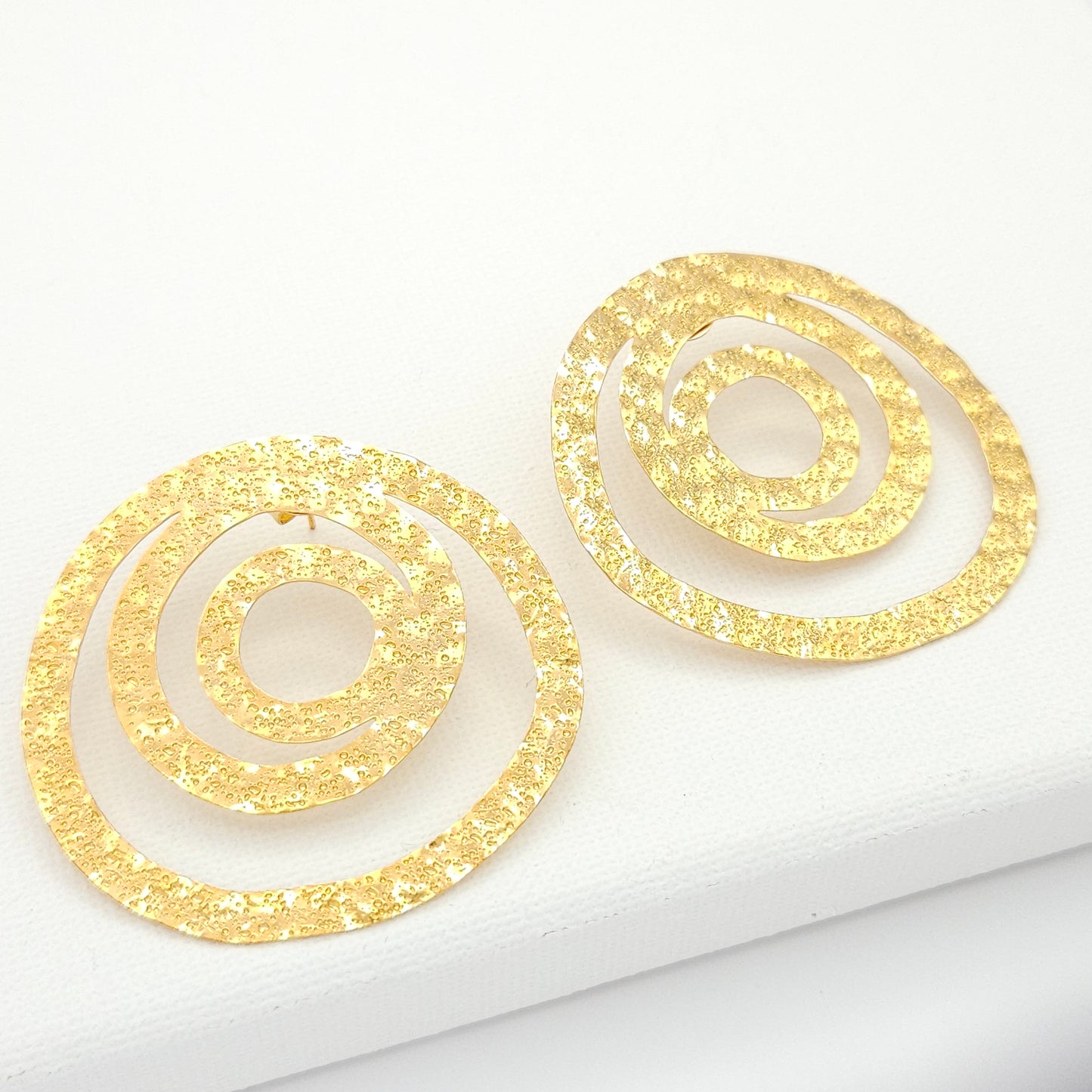Large stud earrings crafted in a captivating spiral design from luxurious 18k gold-plated bronze