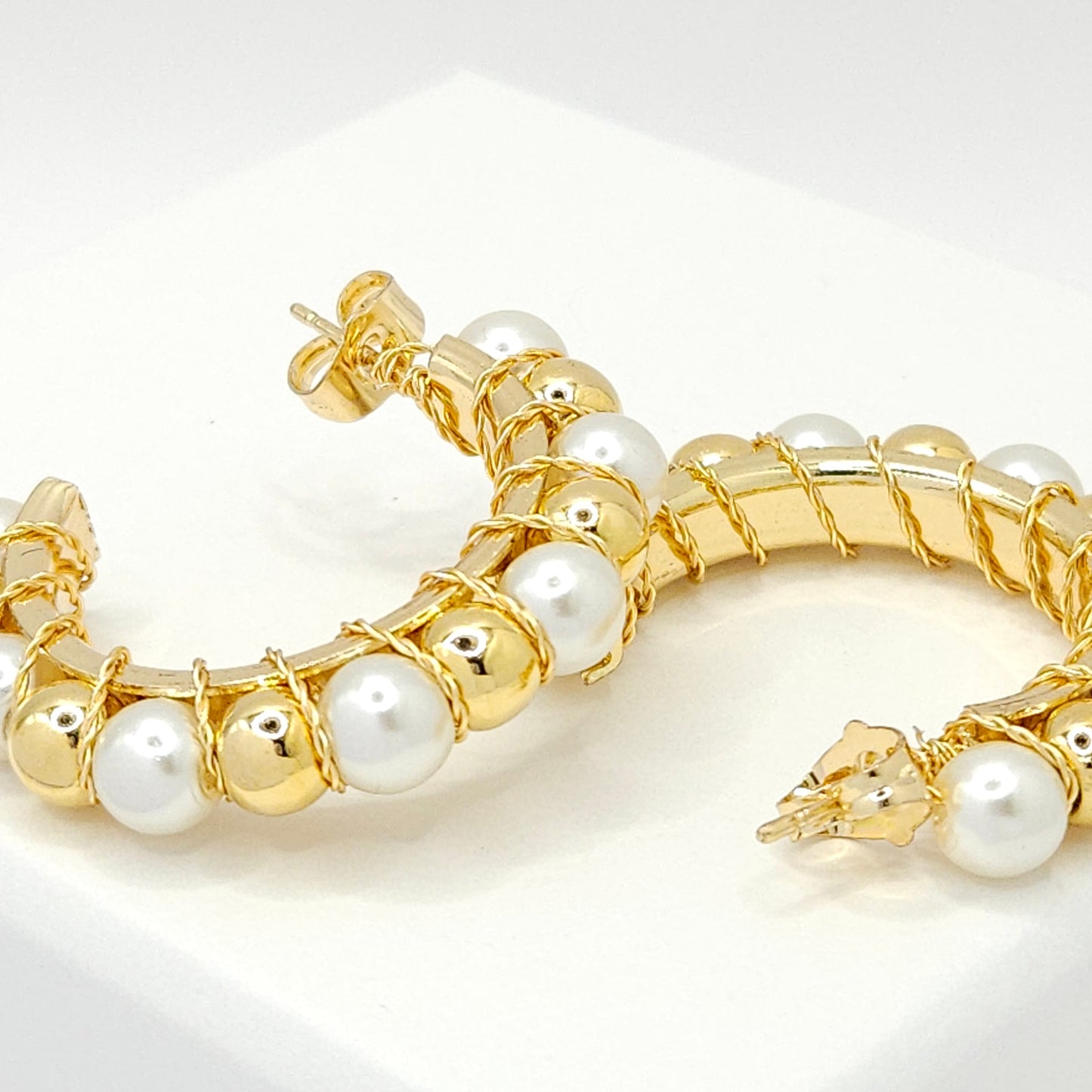 Close-up of golden hoops with pearls and golden spheres