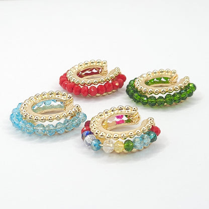 Four golden ear cuffs with faceted rondelle glass beads in green, red, blue, and multicolor, displayed on a white base