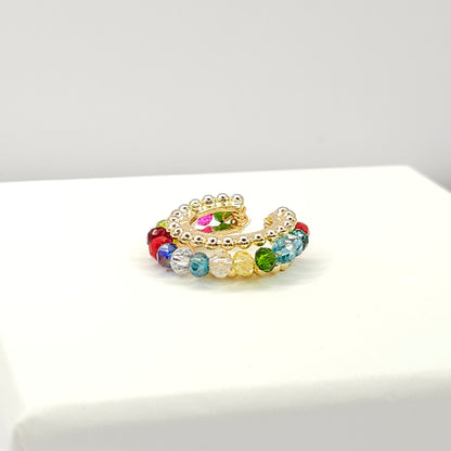 Golden ear cuff featuring an array of multicolour faceted rondelle glass beads lying on a white base