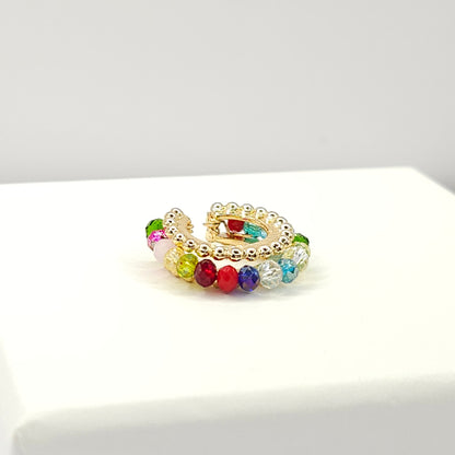 Golden ear cuff featuring an array of multicolour faceted rondelle glass beads lying on a white base