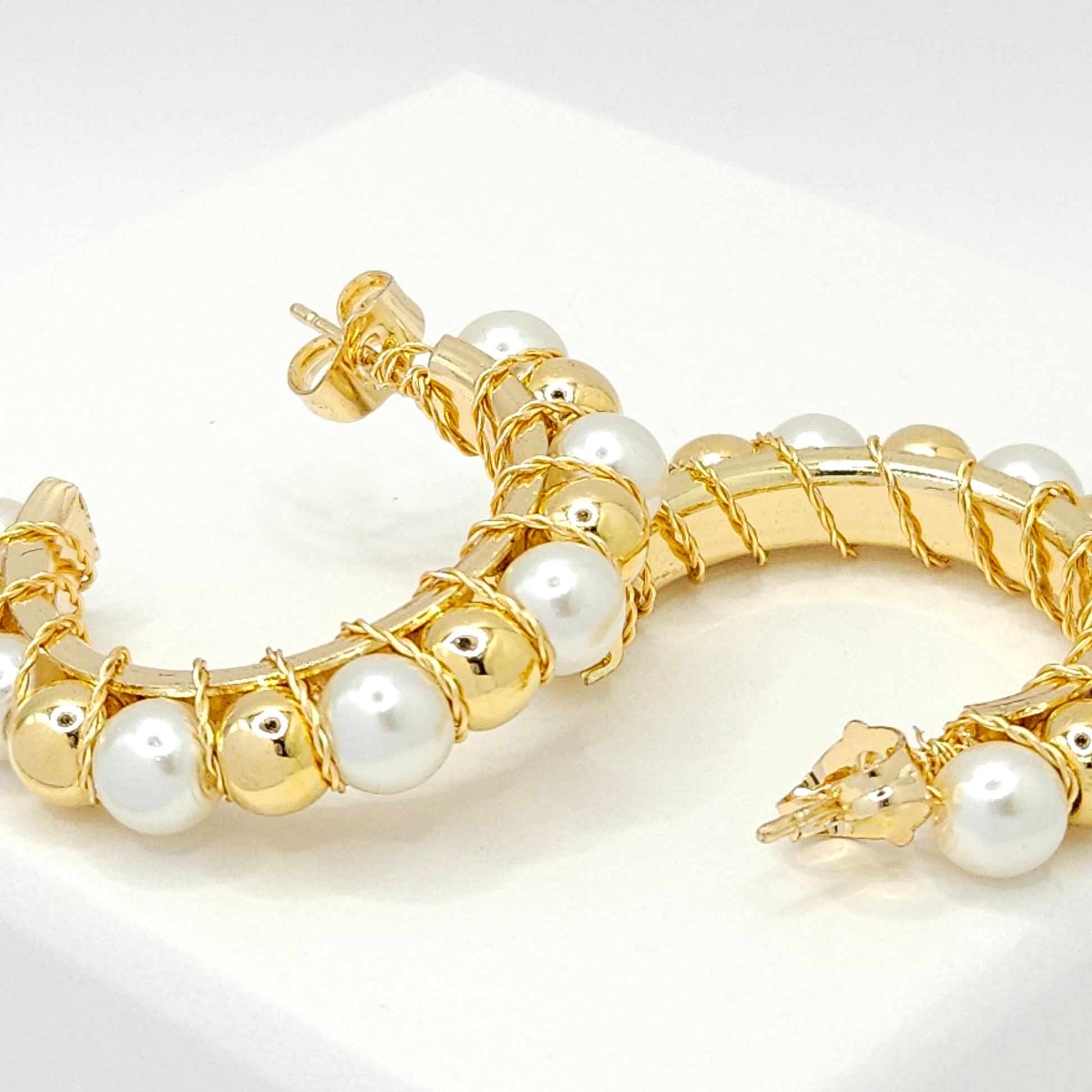 Close-up of golden hoops with pearls and golden spheres