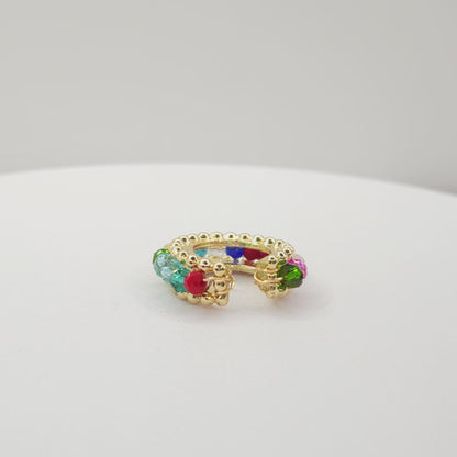 Video of a golden ear cuff featuring an array of multicolour faceted rondelle glass beads lying on a white base, rotating counterclockwise