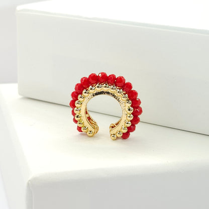 Golden ear cuff featuring an array of red faceted rondelle glass beads standing on a white base