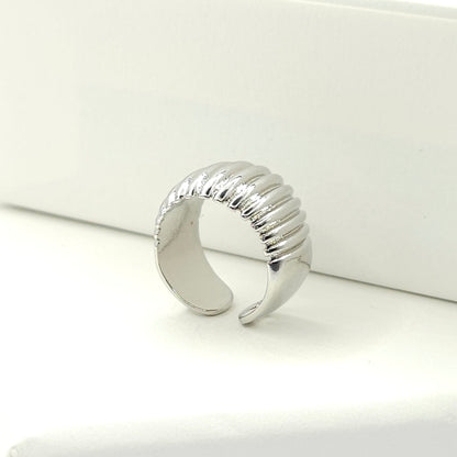 Silver ear cuff adorned with subtle stripes standing on a white base
